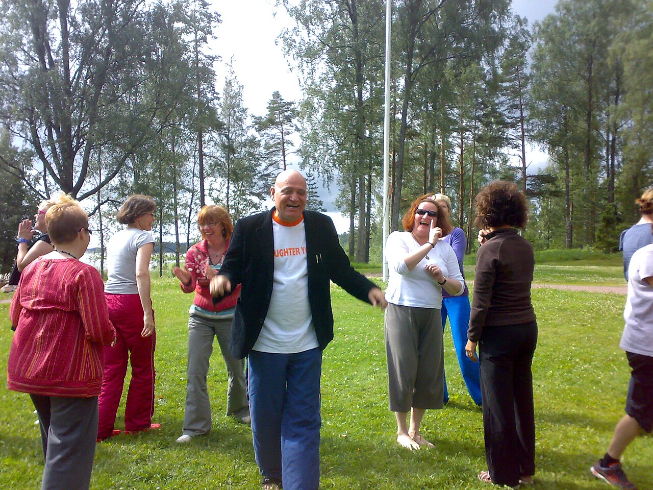 Grupo practicando yoga de la risa con los brazos en alto